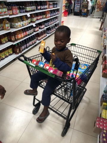 Child in Cart Looking at Juice Time Boxes